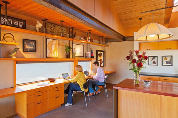 Mary Ellen and Wilf work side by side at a long narrow desk. Wilf designed the suspended shelves. The painting above the desk of the two female figures is by Jeana Edelman.