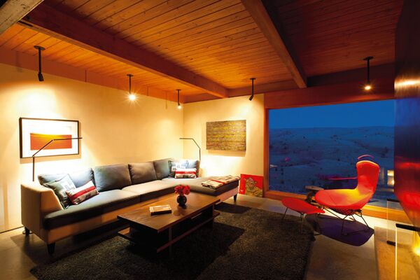The living room seating is oriented to take advantage of the view. The red Bettoia bird chair originally belonged to Wilf's parents. The coffee table with a shelf to store games was designed by EcoPDX. The painting hung on the wall next to the window is by Richard Rollins.